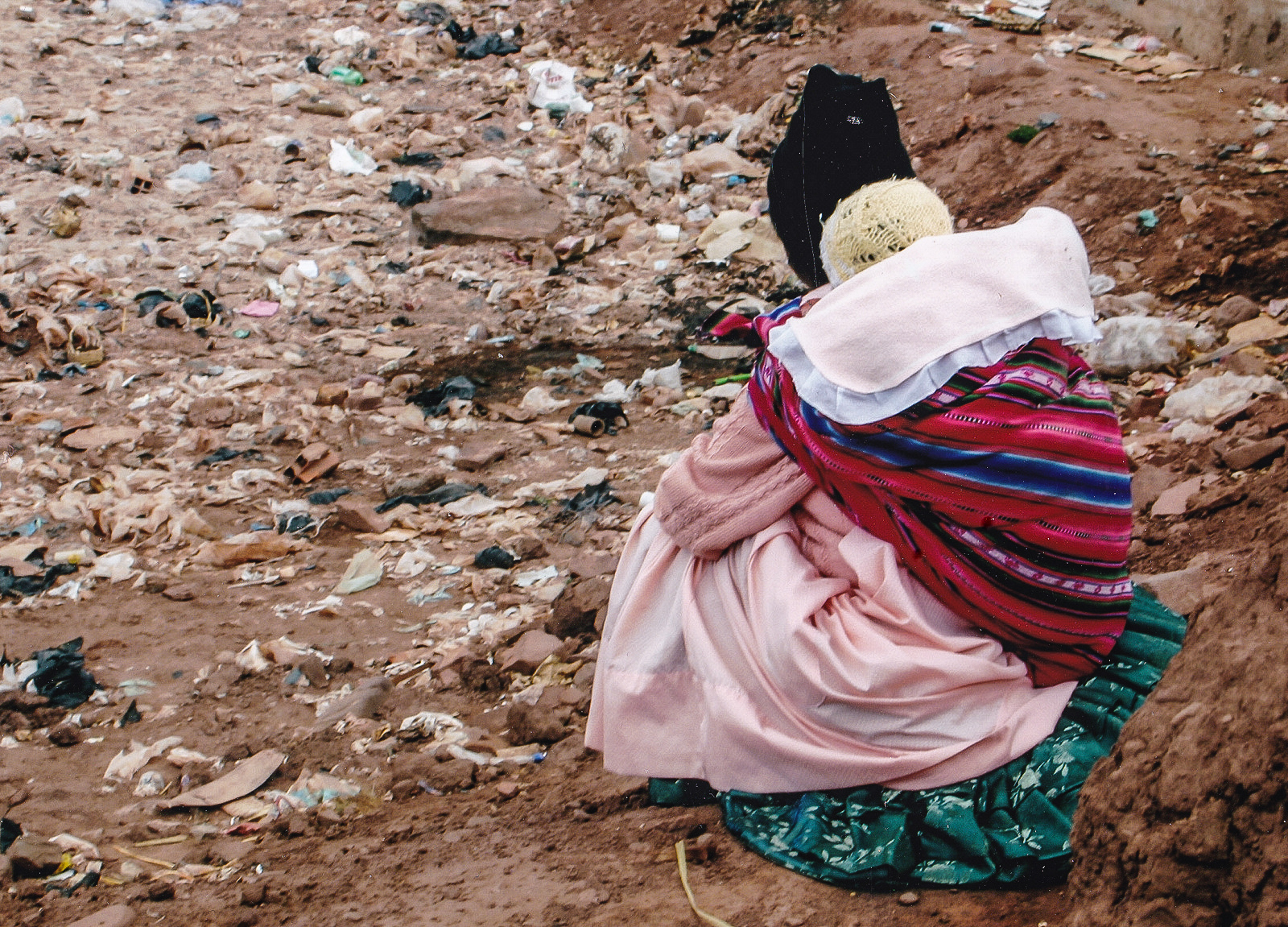 A woman in traditional Bolivian dress carrying her child on her back