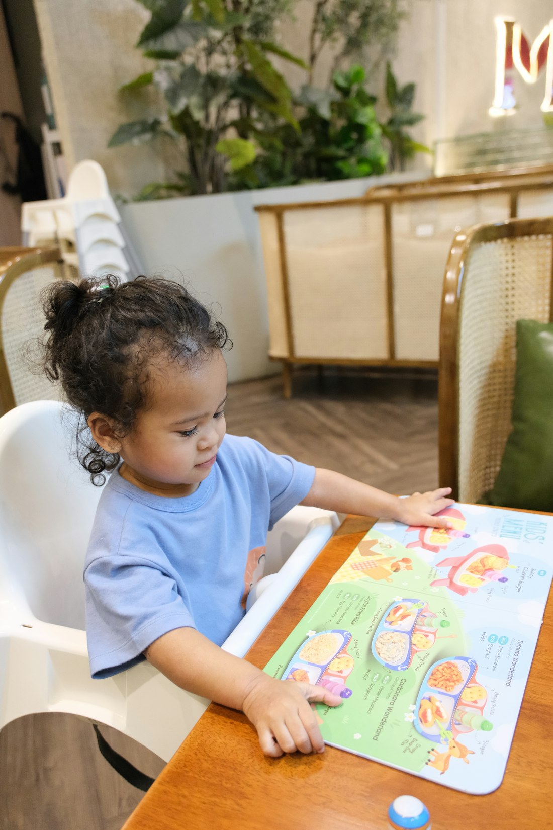 A young child pointing at a colourful picture book page