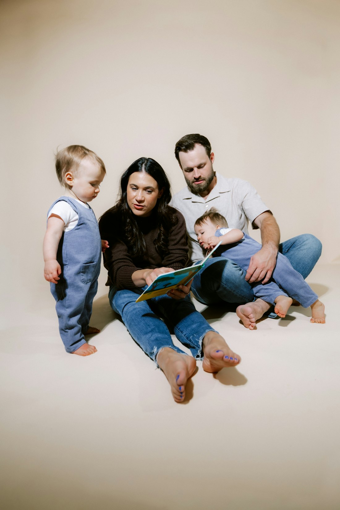 A family reading a picture book together on the floor with their toddler