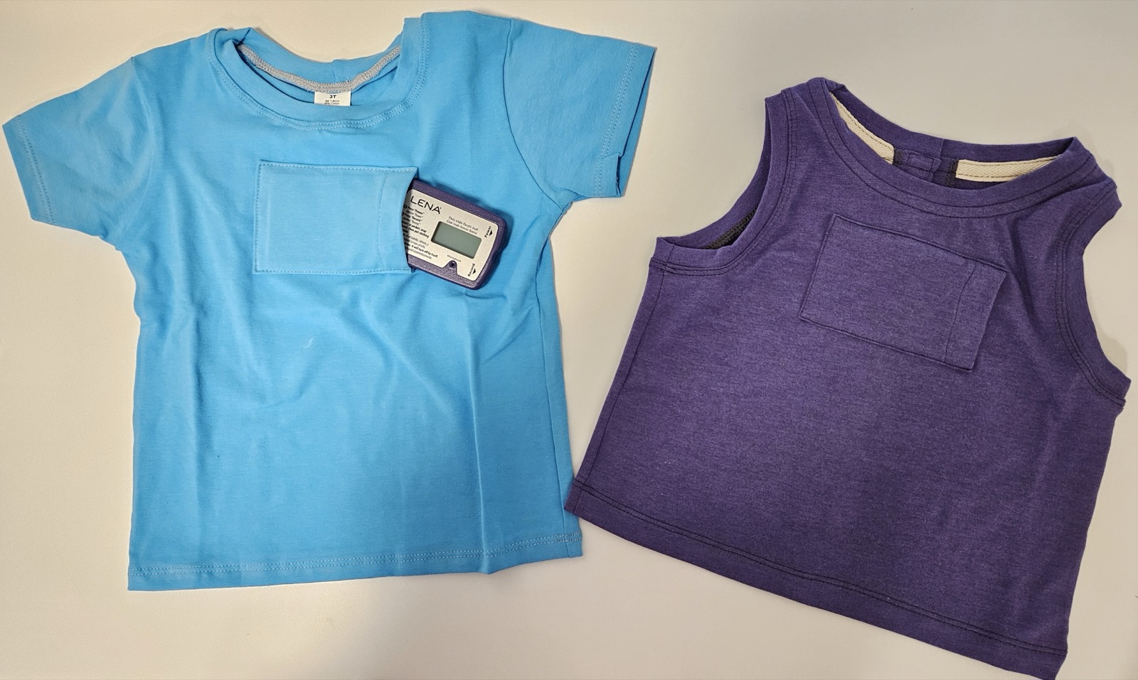 A LENA recorder tucked into the pocket of a child-sized shirt, next to a vest with the same pocket